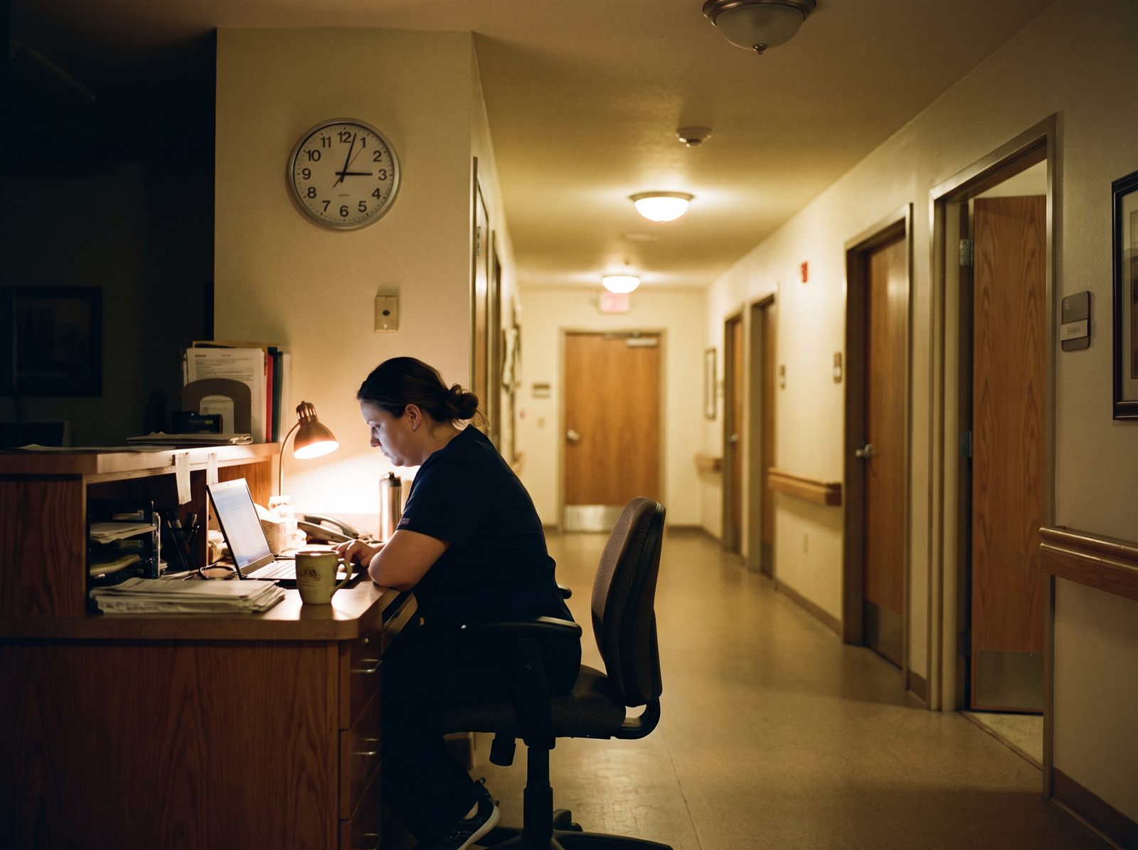 A night nurse at a quiet nurses’ station at the end of a corridor